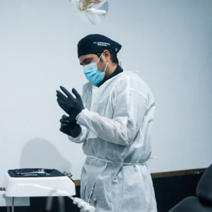 El Dr. Jonathan Bardales ajustando sus guantes y preparándose para dar atención dental